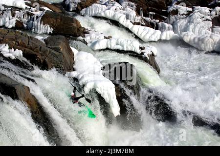 Wildwasser-Kajakfahrer laufen einen fast gefrorenen Wasserfall im Winter.; Great Falls, Potomac River, Maryland. Stockfoto