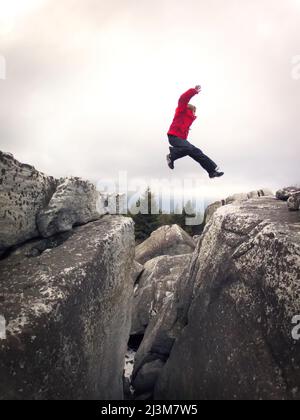 Ian Brown, ein 11-jähriger Junge, springt in der Dolly Sods Wilderness auf eine felsige Schlucht.; Canaan Valley, West Virginia. Stockfoto