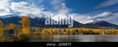 Beschaulicher See Kathlyn, umgeben von herbstlichen Bäumen und schneebedeckten Coast Mountains, vom Lakedrop Inn, Watson's Landing, BC, Kanada aus gesehen Stockfoto