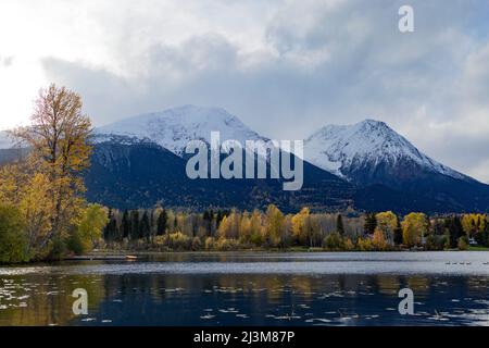 Beschaulicher See Kathlyn, umgeben von herbstlichen Bäumen und schneebedeckten Coast Mountains, vom Lakedrop Inn, Watson's Landing, BC, Kanada aus gesehen Stockfoto