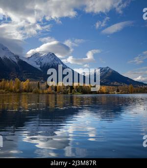 Beschaulicher See Kathlyn, umgeben von herbstlichen Bäumen und schneebedeckten Coast Mountains, vom Lakedrop Inn, Watson's Landing, BC, Kanada aus gesehen Stockfoto