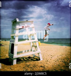 Ein achtjähriger Junge springt von einem Rettungsschwimmer aus.; Nags Head, North Carolina, USA. Stockfoto