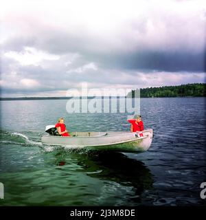 Sieben und acht Jahre alte Cousins fahren ihr kleines Aluminium-Motorboot über Sebago Lake, Maine.; Sebago Lake, Maine, USA. Stockfoto