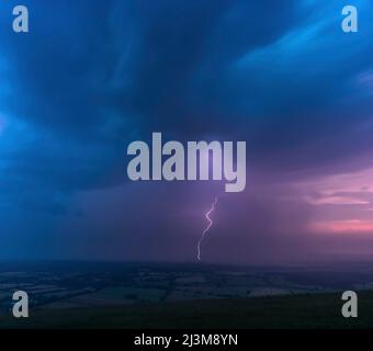 Ein Blitz aus einem Gewitter mit hohem Wetteraufschlag trifft die Landschaft an einem frühen Sommermorgen; Brighton, East Sussex, England Stockfoto