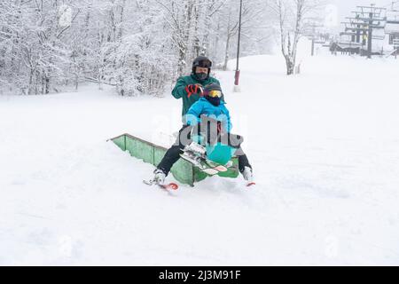 Adaptives Skifahren für ein Mädchen mit Ullrich kongenitaler Muskeldystrophie, in einem Skigebiet mit einem Instruktor Stockfoto