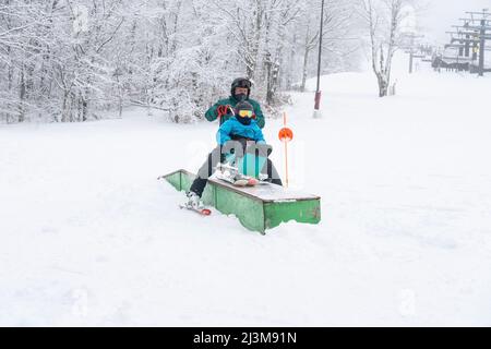 Adaptives Skifahren für ein Mädchen mit Ullrich kongenitaler Muskeldystrophie, in einem Skigebiet mit einem Instruktor Stockfoto