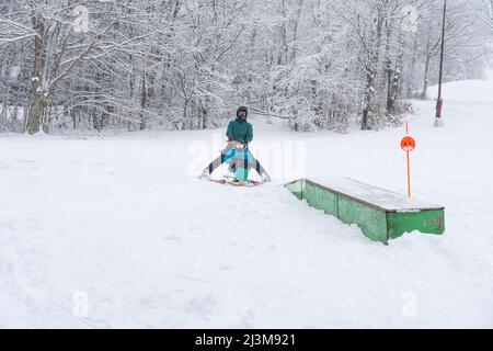 Adaptives Skifahren für ein Mädchen mit Ullrich kongenitaler Muskeldystrophie, in einem Skigebiet mit einem Instruktor Stockfoto