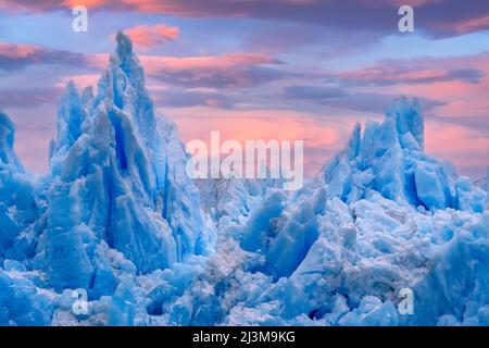 Blaue Eisgipfel einer zerklüfteten Gletschermasse mit leuchtendem rosa Sonnenuntergang am Himmel, South Sawyer Glacier, Tracy Arm, Alaska, USA; Alaska, Vereinigte Staaten von Amerika Stockfoto