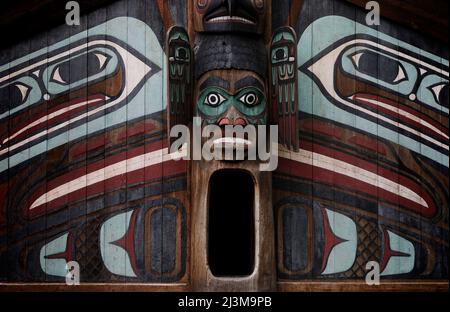 Ein farbenfroher Eingang zu einem Clan der Ureinwohner Alaskas begrüßt Besucher im Totem Bight State Historical Park. Es ist eine Nachbildung eines Gemeindehauses... Stockfoto