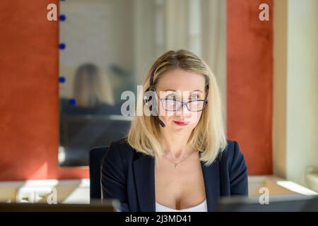 Nachdenkliche Geschäftsfrau blickt mit einem ernsten Blick über die Oberseite ihrer Brille, während sie an ihrem Computer im Büro arbeitet Stockfoto