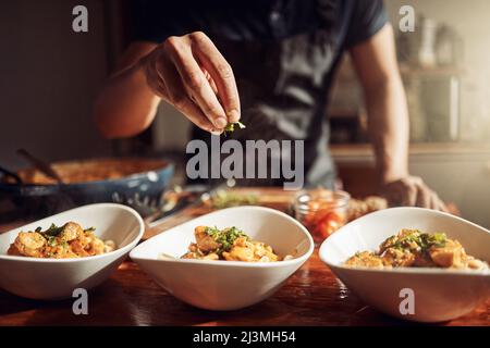 Das Essen ist so gut, wie es das Restaurant macht. Aufnahme eines unverkennbaren Mannes, der zu Hause ein köstliches Essen zubereitet. Stockfoto