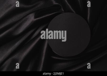 Leere runde Plattform Podium auf schönen schwarzen Hintergrund mit Draperie und welligen Falten aus Seide Satin-Material. Monochromer Hintergrund für Stockfoto