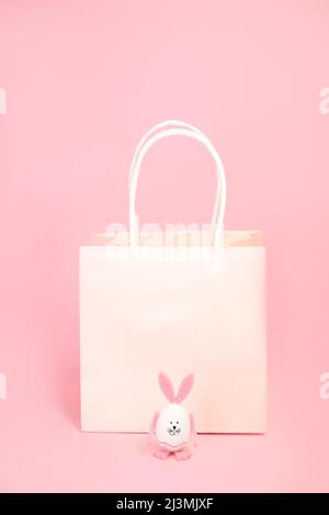 Papier, pinker Beutel und ein Hase mit rosa Ohren und Pfoten auf rosa Hintergrund. Stockfoto