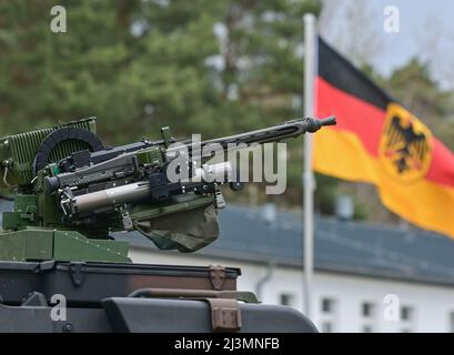 06. April 2022, Brandenburg, Strausberg: Auf dem Gelände der Barnim-Kaserne ist vor den Nationalflaggen Deutschlands ein Maschinengewehr auf einem Dach eines Fahrzeugs zu sehen. Foto: Patrick Pleul/dpa Stockfoto