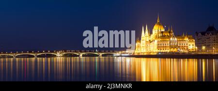 Panoramablick auf die Margaretenbrücke und das Parlamentsgebäude, die sich nachts im Wasser spiegeln Stockfoto