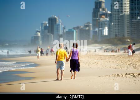 Reifes Paar, das am Strand von Surfers Paradise Hand in Hand ging. Stockfoto