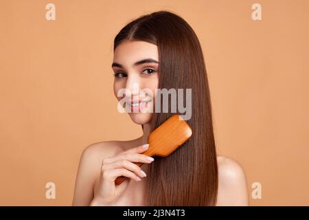 Schöne Frau kämmt ihre Haare mit Holzbürste Stockfoto