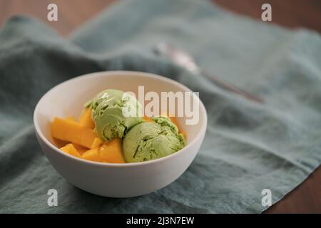 Grüner Matcha-Tee-Eis mit frischer Mango in weißer Schüssel, flacher Fokus Stockfoto