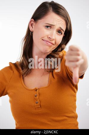 Zeit, um zur Arbeit aufzustehen. Studioaufnahme einer jungen Frau mit Daumen nach unten vor weißem Hintergrund. Stockfoto