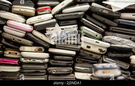 Gebrauchte Telefone übereinander gestapelt. Hintergrund beschädigter Mobiltelefone. Ein paar alte Smartphones. Reparatur- und Wartungsservices für Geräte. Stockfoto