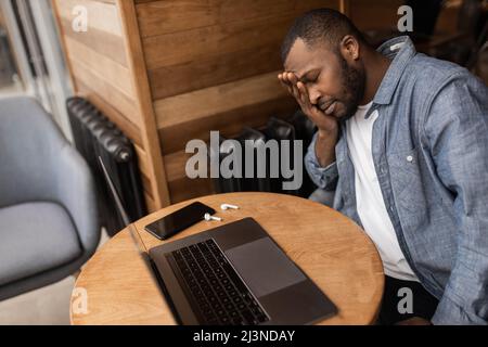 Erschöpfter afroamerikanischer Geschäftsmann, der mit geschlossenen Augen am Schreibtisch saß, einschlief, überarbeiteter junger Mann, unmotivierter Student, der schlief Stockfoto