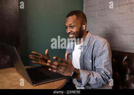 Freundliche Afroamerikaner mit einem Laptop, Blick auf den Bildschirm, chatten mit Kollegen in einem sozialen Netzwerk, lesen gute Nachrichten per E-Mail. Unternehmen Stockfoto