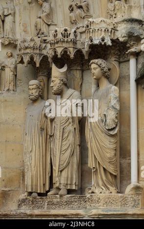 König Clovis I., der Heilige Remigius von Reims und ein Engel, der von links nach rechts auf dem zentralen Portal der Nordfassade der Kathedrale von Reims (Cathédrale Notre-Dame de Reims) in Reims, Frankreich, abgebildet ist. Stockfoto