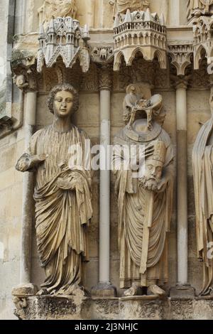 Der Heilige Nicasius von Reims, dargestellt auf dem zentralen Portal der Nordfassade der Kathedrale von Reims (Cathédrale Notre-Dame de Reims) in Reims, Frankreich. Rechts ist der heilige Nicasius abgebildet, links die gotische Engelsstatue. Stockfoto