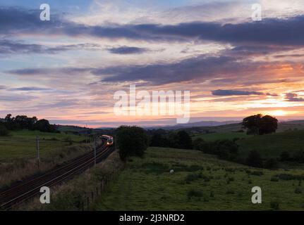 A Virgin fährt den Pendolino-Kippzug der Alstom-Klasse 390 auf der elektrifizierten Hauptlinie der Westküste in Cumbria bei Sonnenuntergang Stockfoto