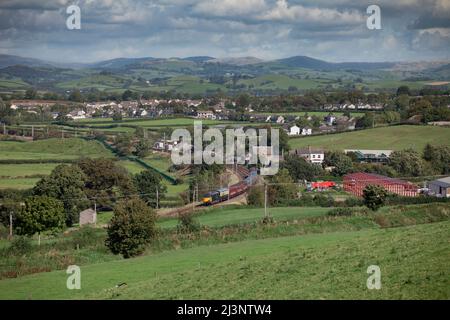 Erhaltene elektrische Lokomotive der Baureihe 87 87002, die Burton in Holme, Cumbria an der Hauptlinie der Westküste mit einem GB Railfreight-Charterzug passiert Stockfoto