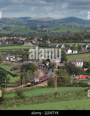 Erhaltene elektrische Lokomotive der Baureihe 87 87002, die Burton in Holme, Cumbria an der Hauptlinie der Westküste mit einem GB Railfreight-Charterzug passiert Stockfoto