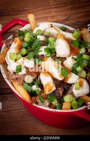 Entenconfit-Poutine-Gericht auf Holztisch Poutine ist eine kanadische Mahlzeit mit pommes Frites-Sauce und Käsekrümmen Stockfoto