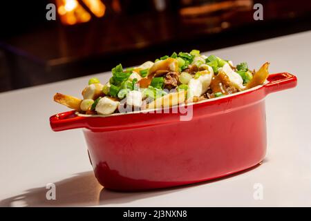 Entenconfit-Poutine-Gericht auf Holztisch Poutine ist eine kanadische Mahlzeit mit pommes Frites-Sauce und Käsekrümmen Stockfoto