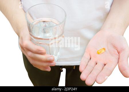 Draufsicht auf einen Mann, der ein Fischöl-Softgel und ein Glas Wasser auf Weiß hält. Nahrungsergänzungsmittel nehmen Konzept. Stockfoto