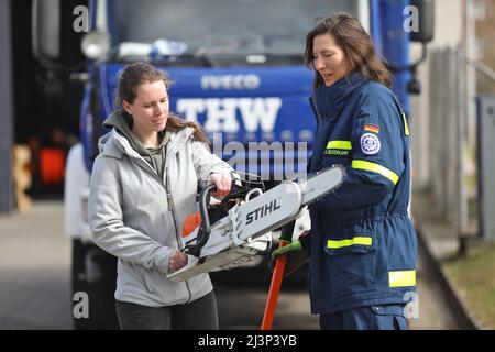 Rostock, Deutschland. 09. April 2022. Alexandra Beckenkamp (r) von der Wismarer Niederlassung des THW erklärt Sophia Kossow (l) aus Rostock eine Rettungssäge. Das Technische Hilfswerk in Rostock repräsentiert symbolisch verschiedene Aktivitäten, die von Schülerinnen bundesweit beim eigentlichen Girls' Day am 28. April ausprobiert werden können. Quelle: Danny Gohlke/dpa/Alamy Live News Stockfoto