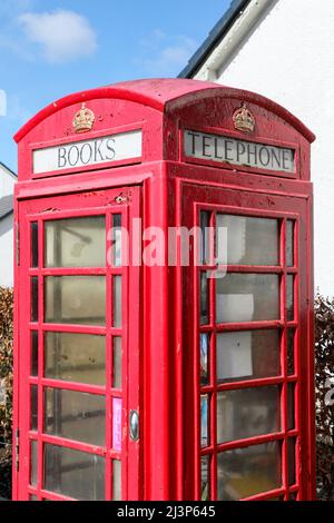 Alte alte, nicht mehr verwendete, traditionelle rote Telefonbox von GPO, jetzt in eine Bibliothek umgewandelt, für die kostenlose Bücherfreigabe, Fenwick, Ayrshire, Schottland, Großbritannien Stockfoto