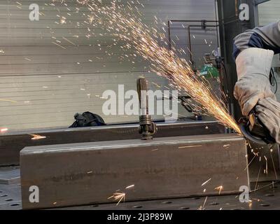 Mann, der mit der Schleifersäge arbeitet und Metall schneidet. Stockfoto