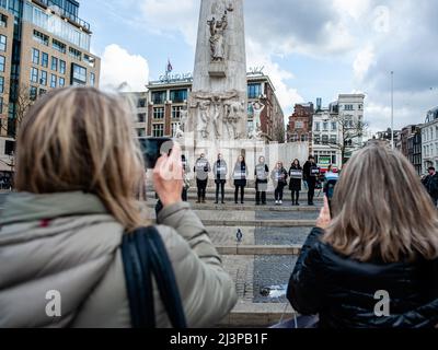 Amsterdam, Niederlande. 09. April 2022. Man sieht Menschen, die Fotos von den Menschen machen, die die Plakate halten. Nach den schrecklichen Ereignissen, die sich diese Woche in Bucha (Ukraine) ereigneten, organisierte die russische Gemeinschaft in den Niederlanden eine Mahnwache, um an die Opfer der Gräueltaten der Russischen Föderation zu erinnern. Am Dam-Platz versammelten sich Menschen in schwarzen Kleidern und mit Plakaten mit den Namen der ukrainischen Städte, die von der russischen Armee angegriffen wurden. Die Veranstaltung war eine stille Traueraktion ohne Ankündigungen oder Reden. Kredit: SOPA Images Limited/Alamy Live Nachrichten Stockfoto