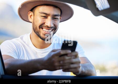 Die Leute machen keine Ausflüge, die Ausflüge nehmen Leute mit. Aufnahme eines jungen Mannes, der ein Telefon benutzte, während er vor seinem Auto stand. Stockfoto