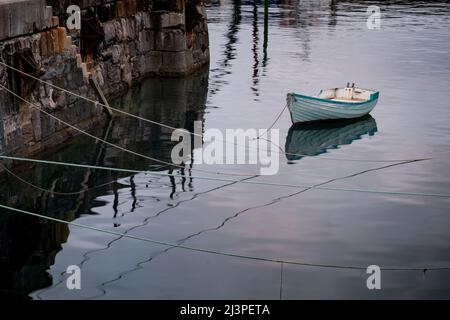 Kleines Schlauchboot aus Holz mit Anlegeseilen, das im Hafen von mevagissey in cornwall verankert ist Stockfoto