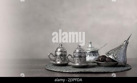 Silberne Kaffee- oder Teetasse und Zuckergläser mit Datteln Stockfoto