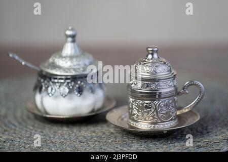 Silberne Kaffeetasse und silberne Zuckergläser.Nahaufnahme. Stockfoto