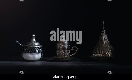 Silberne Kaffeetasse und Zuckergläser mit Datteln. Stockfoto