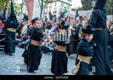 Während der Prozession werden die Kinder von einer der "Cofradias" (Bruderschaften) auf den Straßen spazieren gesehen. In Spanien heißt die Karwoche „Semana Santa“ und wird mit unvergleichlicher Pracht und Emotion gefeiert. Es kommt mit religiösen Prozessionen im ganzen Land, die die Straßen mit dem Beat der Trommeln, Blumen und religiösen Skulpturen füllen. Stockfoto