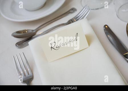 Reserviertes Zeichen an einer Tischeinstellung mit weißer Tischdecke Stockfoto