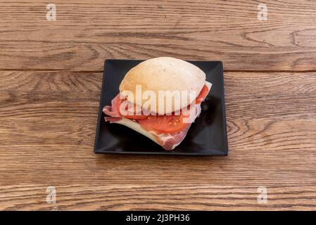 Dorfbrot-Muffin mit Serrano-Schinken, Tomaten und Olivenöl Stockfoto