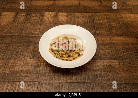 Tagliatelle ist eine Art langgestreckter Teig, klein in der Breite und in der Form abgeflacht, aus dem sich die asciutte Pasta italienischer Herkunft ergibt. Stockfoto