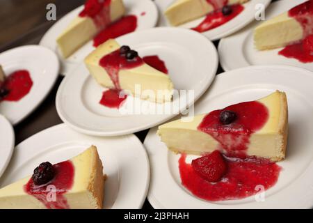 High-Angle-Vollformatsbild von Käsekuchen-Platten mit Erdbeer-, Kirsch- und Blackberry-Kompott Stockfoto