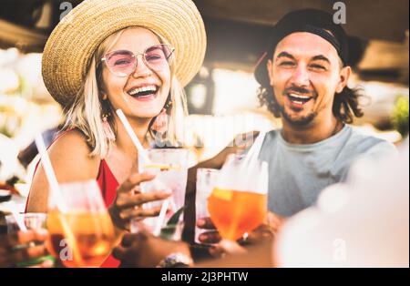 Trendiges Paar, das Spaß mit dem Trinken von ausgefallenen Cocktails auf der Strandparty hat - Sommerfreude und echtes Lifestyle-Konzept mit jungen Leuten bei der Festival Happy Hour Stockfoto