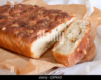 Weißes Parmesan- und Knoblauchbrot mit goldbrauner Kruste in Pergament, selektiver Fokus. Hausgemachte Brotherbereitung Stockfoto